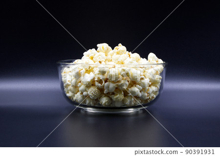 Popcorn in a glass cup placed on black background. 90391931