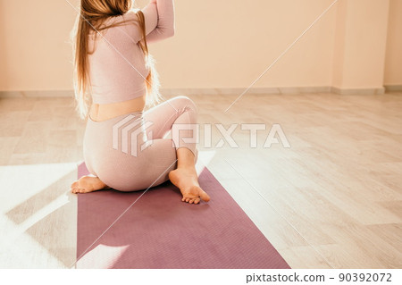 Young sporty woman, fitness instructor in pink sportswear doing stretching and pilates on yoga mat in the studio with mirror. Female fitness yoga routine concept. Healthy lifestyle and harmony. 90392072