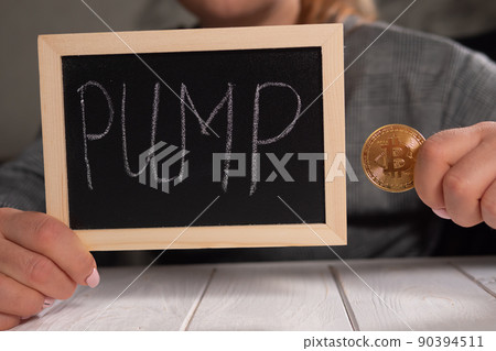 Close-up of a woman holding a board with the inscription PUMP and a gold bitcoin Close-up of a woman holding a board with the inscription PUMP and a gold bitcoin 90394511