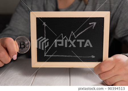 A woman holding a gold bitcoin and a board with a graph. Cryptocurrency. 90394513