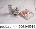 Close-up of a stack of hundred-dollar bills and five thousand rubles on a table. 90394549
