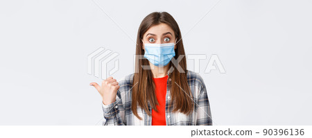 Coronavirus outbreak, leisure on quarantine, social distancing and emotions concept. Astonished and impressed cute woman in medical mask showing way, talking about banner on left side Coronavirus outbreak, leisure on quarantine, social distancing and emotions concept. Astonished and impressed cute woman in medical mask showing way, talking about banner on left side 90396136