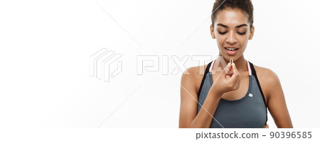 Healthy and Fitness concept - Closeup portrait of beautiful African American taking a pill of Cod liver oil. Isolated on white studio background. 90396585