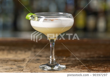 Vanilla Sour cocktail with egg white and lemon juice  on the bar. Blurred background. 90397297