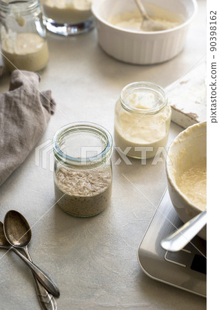 Sourdough starter in glass jars. Homemade breadmaking concept, busy lifestyle scene of baking at home. Sustainable living Sourdough starter in glass jars. Homemade breadmaking concept, busy lifestyle scene of baking at home. Sustainable living 90398162