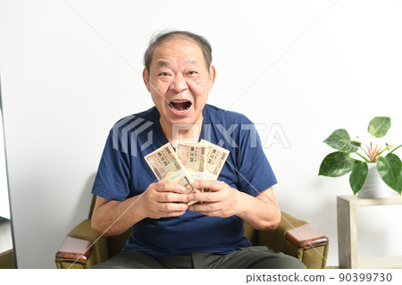 A smiling senior man with a wad of bills 90399730
