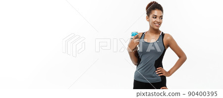 Healthy and Fitness concept - beautiful African American girl in sport clothes holding water bottle after workout. Isolated on white studio background 90400395