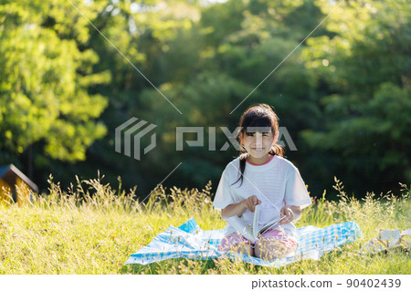 An elementary school girl reading in a summer park An elementary school girl reading in a summer park 90402439