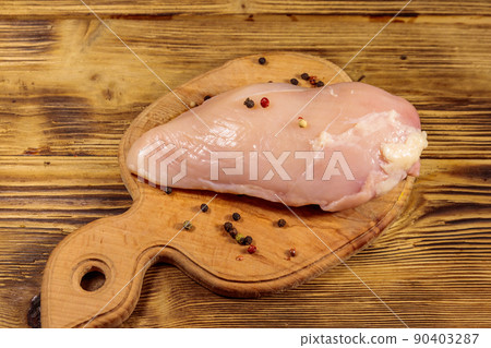 Raw chicken breast on cutting board on wooden table 90403287