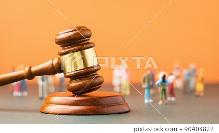Judicial gavel and plastic toy men on a colored background, a concept on the topic of litigation in society 90403822