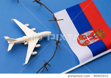 Toy plane, flag and barbed wire on a blue background, the concept of the closed air border of Serbia 90403833