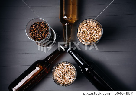 bottles with craft beer and beer glasses with barley malt on a grey wooden background. Ale or lager from pilsner malt. homemade home-brewed beer. bottles with craft beer and beer glasses with barley malt on a grey wooden background. Ale or lager from pilsner malt. homemade home-brewed beer. 90404997