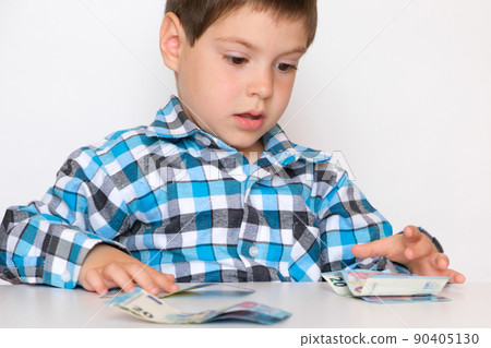 A 4-year-old boy counts money, holds euros in his hands. Teaching children financial literacy, pocket money. A 4-year-old boy counts money, holds euros in his hands. Teaching children financial literacy, pocket money. 90405130