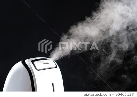 Humidifier with steam jet on a black background. Humidity in the room, maintaining the microclimate in the apartment. Humidifier with steam jet on a black background. Humidity in the room, maintaining the microclimate in the apartment. 90405137