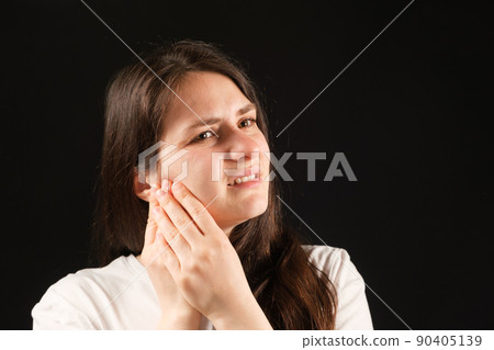 A woman holds her hands to a sore temporomandibular joint, dysfunction and pain, dislocated jaw, problems of wisdom teeth. A woman holds her hands to a sore temporomandibular joint, dysfunction and pain, dislocated jaw, problems of wisdom teeth. 90405139
