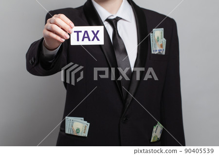 Businessman with us dollar cash money in his pockets holding white card with tax inscription Businessman with us dollar cash money in his pockets holding white card with tax inscription 90405539