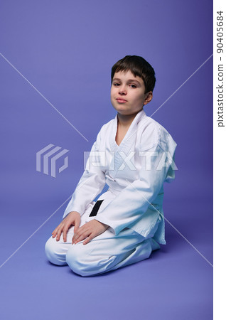 European teenage boy - aikido fighter in a white kimono during the practice of oriental martial arts. European teenage boy - aikido fighter in a white kimono during the practice of oriental martial arts. 90405684
