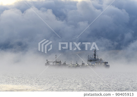 Vessel engaged in dredging. Dredger working at sea. Ship excavating material from a water environment. Strong fog in Arctic sea. Construction Marine offshore works. Dam building, crane, barge, 90405913