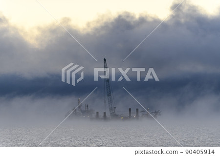 Barge with crane. Dredger working at sea. Strong fog in Arctic sea. Construction Marine offshore works. Dam building, crane, barge, dredger. 90405914
