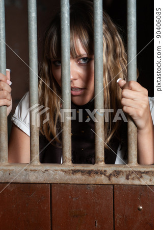 female rider locked in the stables behind bars 90406085