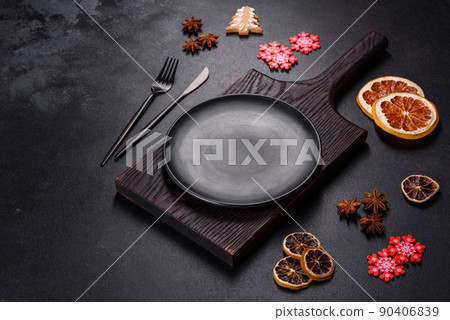 Christmas table setting with empty black ceramic plate, fir tree and black accessories Christmas table setting with empty black ceramic plate, fir tree and black accessories 90406839