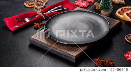 Christmas table setting with empty black ceramic plate, fir tree and black accessories Christmas table setting with empty black ceramic plate, fir tree and black accessories 90406846