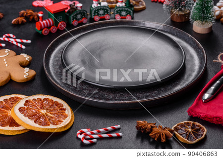 Christmas table setting with empty black ceramic plate, fir tree and black accessories Christmas table setting with empty black ceramic plate, fir tree and black accessories 90406863