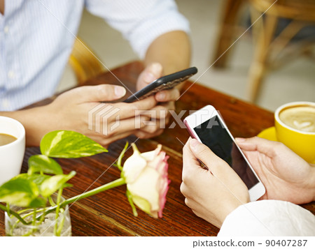 hands of man and woman using mobile phones in coffee shop hands of man and woman using mobile phones in coffee shop 90407287