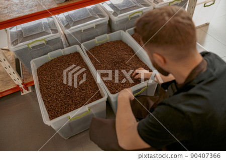 Male worker in uniform inspection freshly roasted coffee beans on manufacturing  90407366