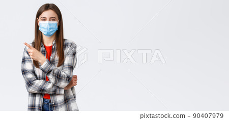 Coronavirus outbreak, leisure on quarantine, social distancing and emotions concept. Cheerful smiling caucasian woman in medical mask, pointing finger upper left corner, recommend link or product 90407979