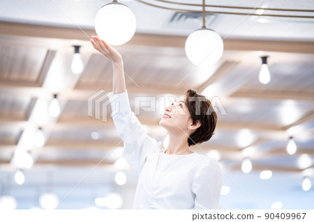 A woman holding her hand over the lighting (SDGs / ecology image) 90409967