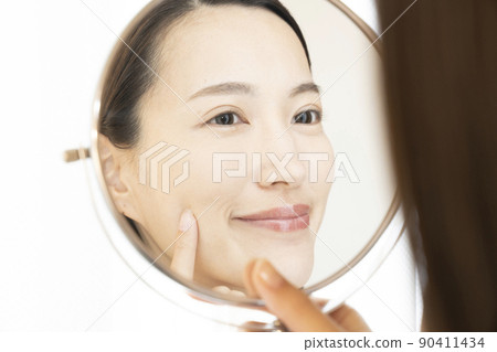 A woman looking at a mirror and smiling A woman looking at a mirror and smiling 90411434