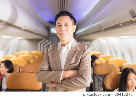 In the plane, there is a young passenger. portrait of a man standing in an airplane aisle In the plane, there is a young passenger. portrait of a man standing in an airplane aisle 90413275