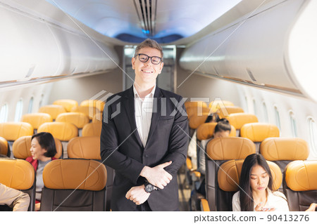 In the plane, there is a young passenger. portrait of a man standing in an airplane aisle In the plane, there is a young passenger. portrait of a man standing in an airplane aisle 90413276