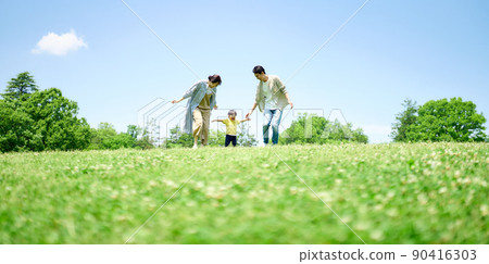 Family playing around on the green hill 90416303