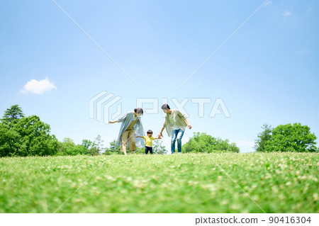 Family playing around on the green hill 90416304