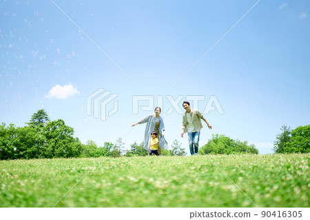 Family playing around on the green hill 90416305