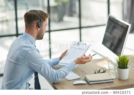 Man with headphones and laptop working in office Man with headphones and laptop working in office 90418371