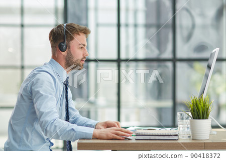 Man with headphones and laptop working in office Man with headphones and laptop working in office 90418372