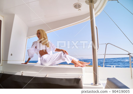 Beautiful young blond woman sitting on catamaran at sunny summer day Beautiful young blond woman sitting on catamaran at sunny summer day 90419005
