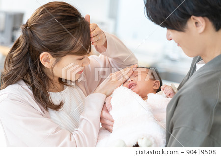 Young mom and dad measure the heat by putting their hands on the forehead of a crying baby Young mom and dad measure the heat by putting their hands on the forehead of a crying baby 90419508