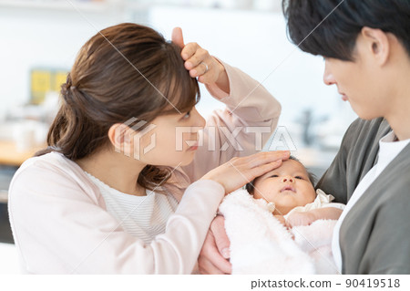 年輕的媽媽和爸爸把手放在嬰兒的額頭上測量熱量 90419518