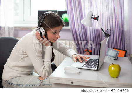 A teenager listens to a lecture from her school on during remote learning. A teenager listens to a lecture from her school on during remote learning. 90419716