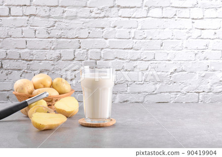 Vegan potato milk and potato on grey stone table background. Plant based alternative milk replacer and lactose free 90419904