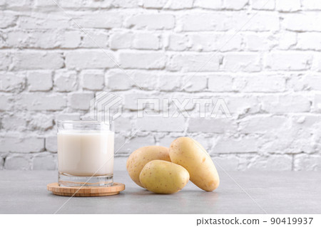 Vegan potato milk and potato on grey stone table background. Plant based alternative milk replacer and lactose free 90419937