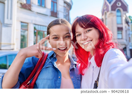 Two happy teenage females taking selfie portrait together, on city street Two happy teenage females taking selfie portrait together, on city street 90420618