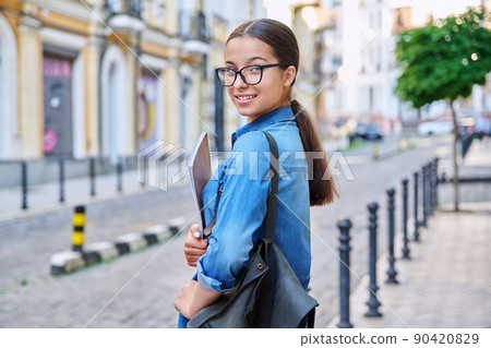 Outdoor portrait of smiling teenage female student looking at camera in city 90420829