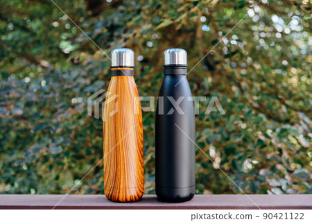 Reusable thermo bottles against green nature summer background. 90421122