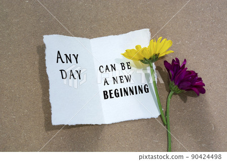Motivational quote on torn white paper with sunflower on wooden table background 90424498