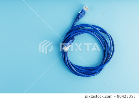 A coil of an Internet network cable for data transmission on a blue background 90425355